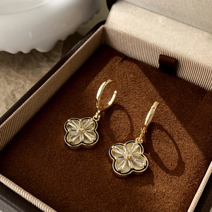 Detail of gold clover earrings with mother of pearl and zircon in a brown velvet box