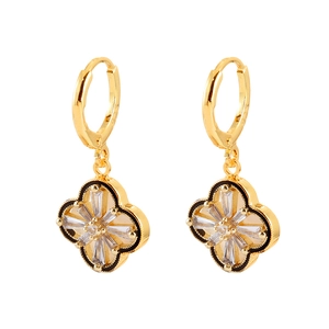 Detailed view of gold hoop earrings with black clover pendants and white crystals