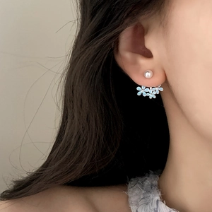 Elegant floral pearl earrings with light blue enamel petals shown on model ear