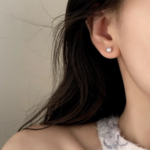 Close-up of elegant round pearl stud earring worn on model for a graceful aesthetic