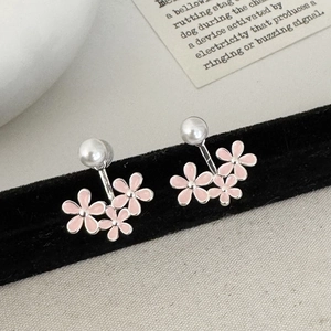 Close-up of pink enamel floral earrings with white pearls on a black velvet display