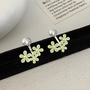 Macro view of light green enamel flower stud earrings with silver metal details on velvet