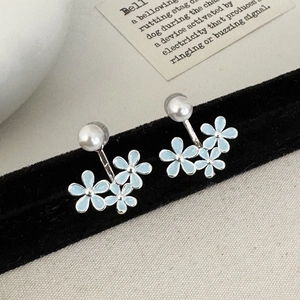Detail of light blue floral enamel earrings with pearls on a black velvet display stand