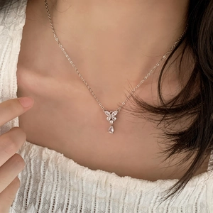 Close-up of butterfly zircon pendant necklace with teardrop crystal on a white lace collar