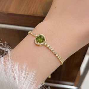 Golden chain bracelet with large green zircon and pavé stones on model wrist