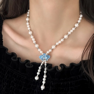 Collier de perles élégant avec pendentif fleur bleue et glands porté pour un style chic