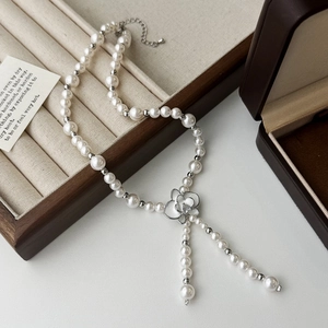 Détail du pendentif fleur en émail et perles sur un élégant collier de style français