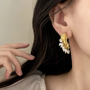 Elegant French style gold pleated earrings with pearls worn on model's ear