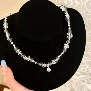 Detail of beaded crystal necklace with small silver bell pendant on display