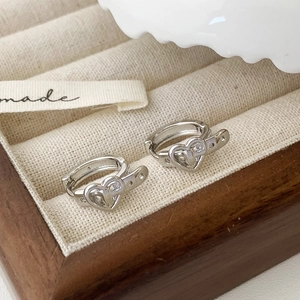 Elegant silver heart-shaped hoop earrings with crystals in a wooden jewelry box