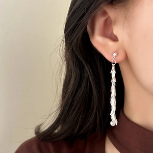 Elegant long leaf tassel earrings in silver finish worn by a model in a close-up shot