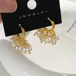 Détail de créoles dorées ornées d'élégants pompons de perles sur une carte à bijoux