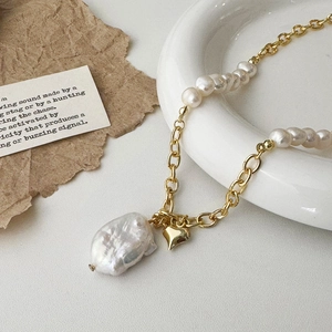 Close-up of Baroque pearl necklace with gold heart pendant and mixed link chain