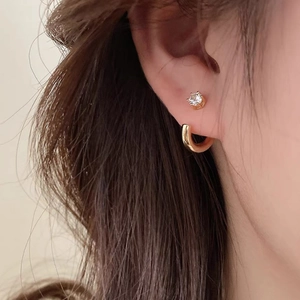 Minimalist C-shaped gold hoop and sparkling zircon stud earring set worn by a model