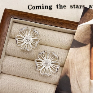 Elegant hollow floral earrings in silver finish displayed in a vintage jewelry box