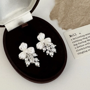 Detailed view of silver flower earrings with white pearl tassels in a vintage jewelry box