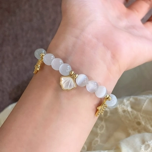 Bracelet perlé étoile et opale avec pendentif coquillage doré porté sur poignet et dentelle
