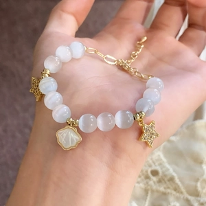 Bracelet élégant en œil de chat avec pendentifs étoile et coquillage dorés au poignet