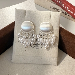 Détail de boucles d'oreilles en métal brossé argenté avec pampilles en perles chic