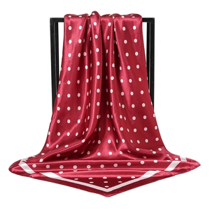 Detailansicht eines roten gepunkteten Quadratschals mit elegantem Fall und Satin-Textur-Glanz