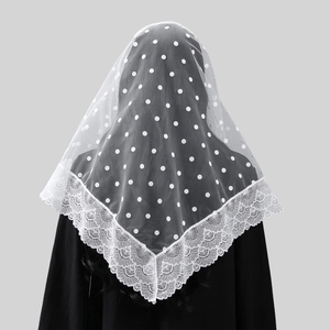 Detail of white lace bridal veil with floral embroidery and polka dot mesh on black background