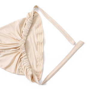 Dettaglio del turbante in tessuto plissettato beige con nastri regolabili a coulisse