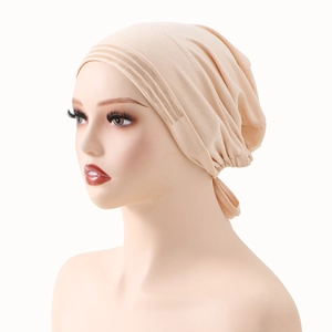Dettaglio del turbante beige con sottili nervature e trama in maglia plissettata