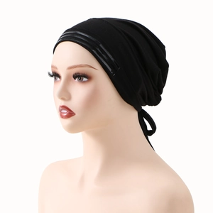 Dettaglio del turbante elastico nero con bordo lucido e coulisse regolabile sul retro