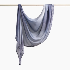 Detail eines leichten voile Schals mit blauem Farbverlauf und Blumenmuster am Rand
