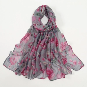Dettaglio di sciarpa in voile con eleganti fiori rosa su tessuto grigio leggero e morbido
