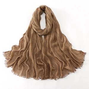 Detailed texture of dark brown wrinkled cotton scarf featuring delicate fringe edges