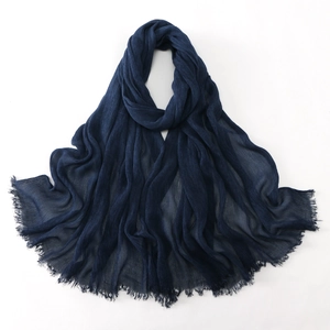 Detailed texture of dark blue pleated cotton scarf with frayed fringe edges