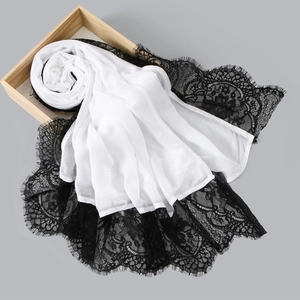 White long scarf with black eyelash lace edge displayed on a wooden tray