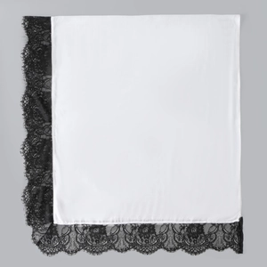 Close-up of elegant white silky fabric with intricate black floral lace trim detailing