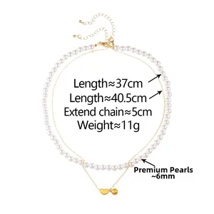 Detail of double-layer necklace with 6mm white pearls and gold heart pendant on white background