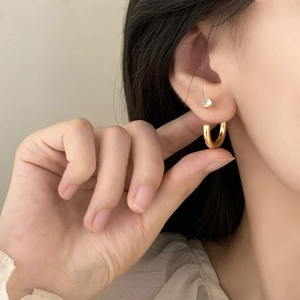 Minimalist gold C-shaped earring and round zircon stud set shown on a female model