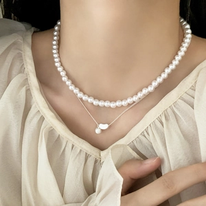 Elegant double-layer necklace featuring lustrous pearls and a silver bean pendant charm