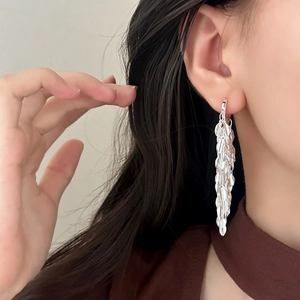 Boucles d'oreilles pendantes feuilles argentées avec paillettes métalliques sur modèle