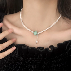 French vintage pearl necklace with green clover stone pendant worn on a model's neck