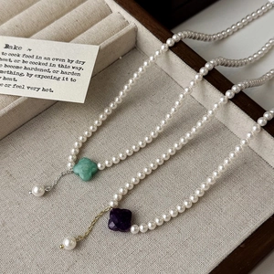 Elegant four-leaf clover pearl necklaces in green and purple stones on jewelry tray