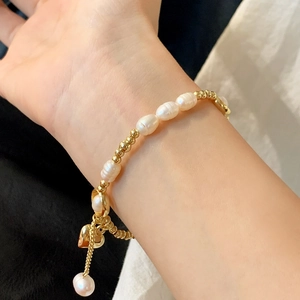 Elegant freshwater pearl bracelet with gold beads and heart pendant on wrist