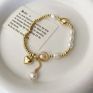 Detail of freshwater pearl bracelet with golden heart pendant on vintage card background