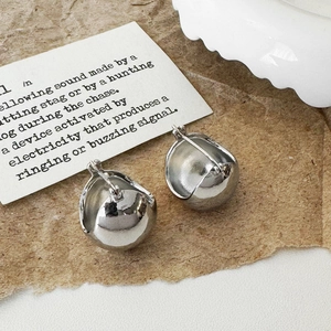 Detail of silver drop earrings with a polished mirror finish on a rustic paper background