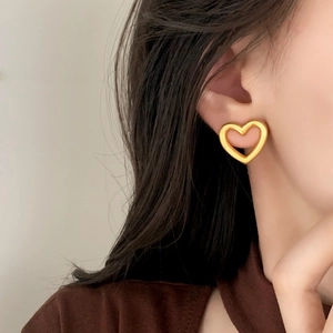 Minimalist gold hollow heart stud earrings for women shown on a model ear lobe