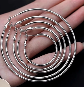 Polished silver geometric hoop earrings in four different sizes displayed on hand