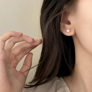 Élégantes boucles d'oreilles perles d'eau douce blanches sur mannequin de style minimaliste