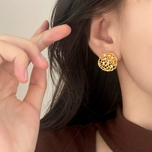 Elegant gold hollow mesh earrings with white zircons shown on a model's ear