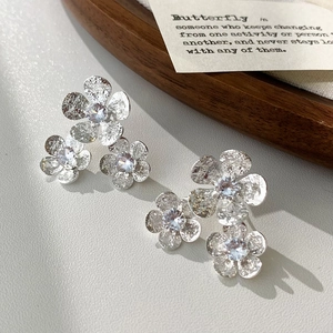 Close-up of silver flower stud earrings with hammered texture and zircon center stones