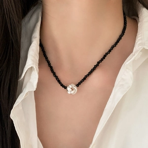 Collier élégant en perles noires avec pendentif noeud torsadé en argent sur modèle