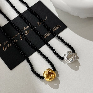Collier élégant en perles noires avec pendentif nœud torsadé en métal doré et argent